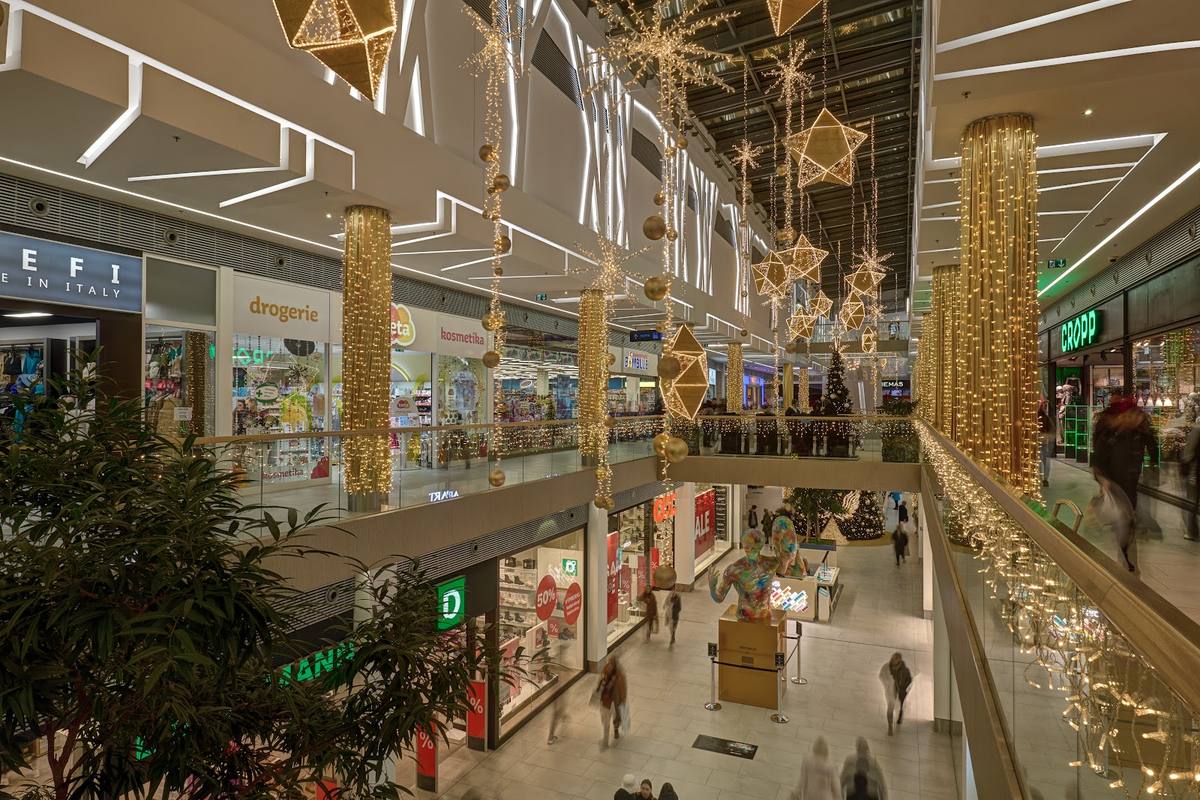 Praznična okrasitev nakupovalnega središča z visečimi zvezdami in svetlobnimi stebri.